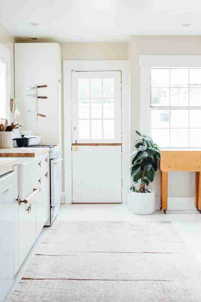 A kitchen with white cabinets and a rug.
