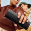 Person holding a Sonos wireless speaker with another person dancing in the background.